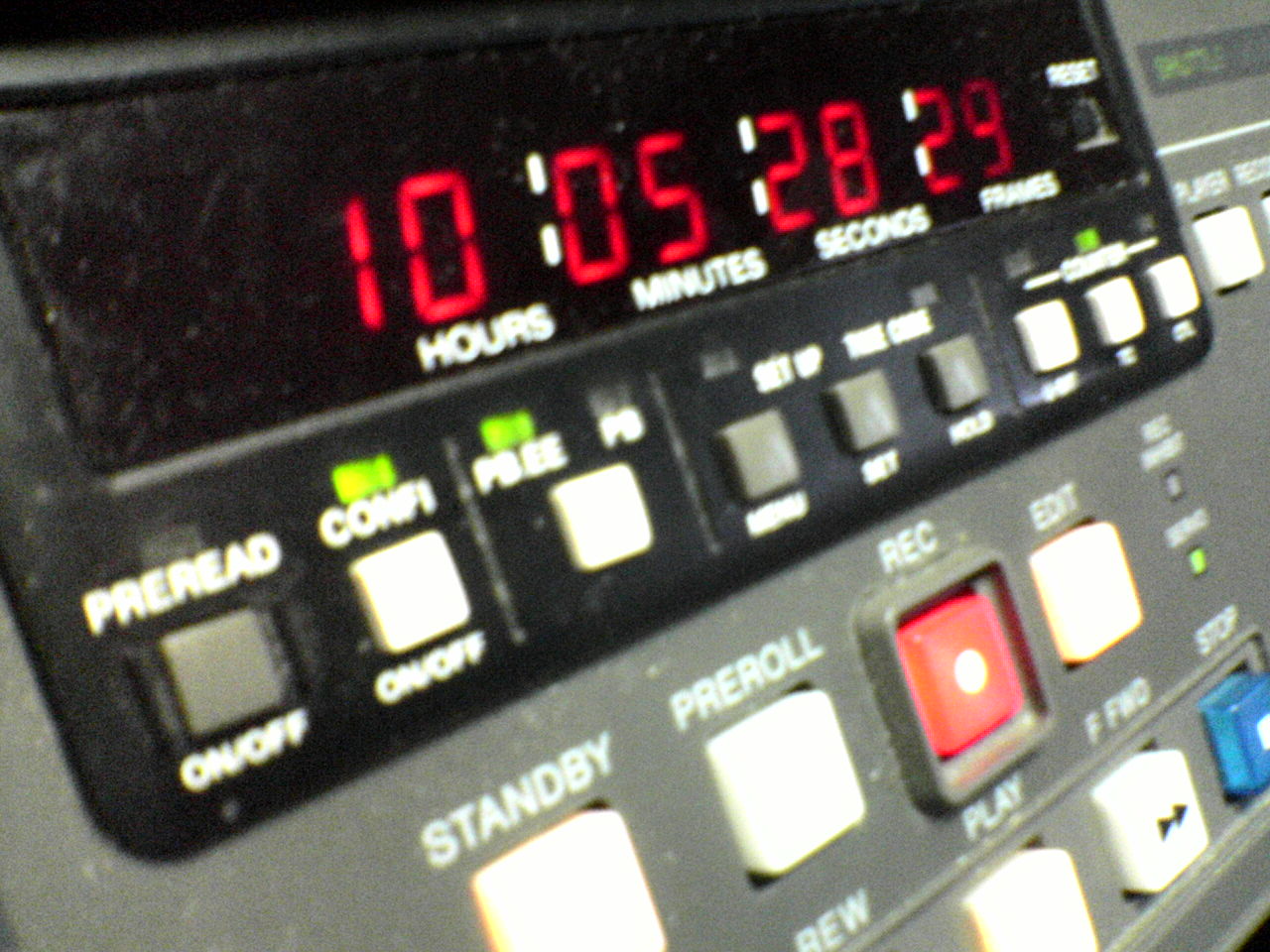 A close up image of a piece of hardware with multiple colored buttons with labels such as `standby` and `preroll,` and with a large red LED display displaying 10 hours, 05 minutes, 28 seconds and 29 frames.