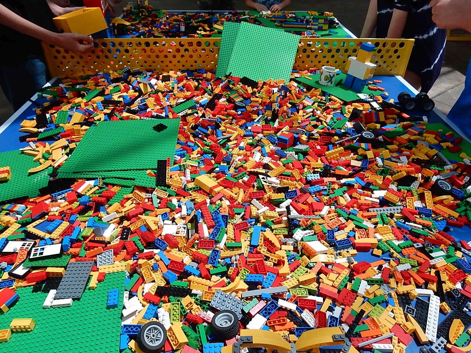A photograph of a large table filled with thousands of colorful Lego building blocks.