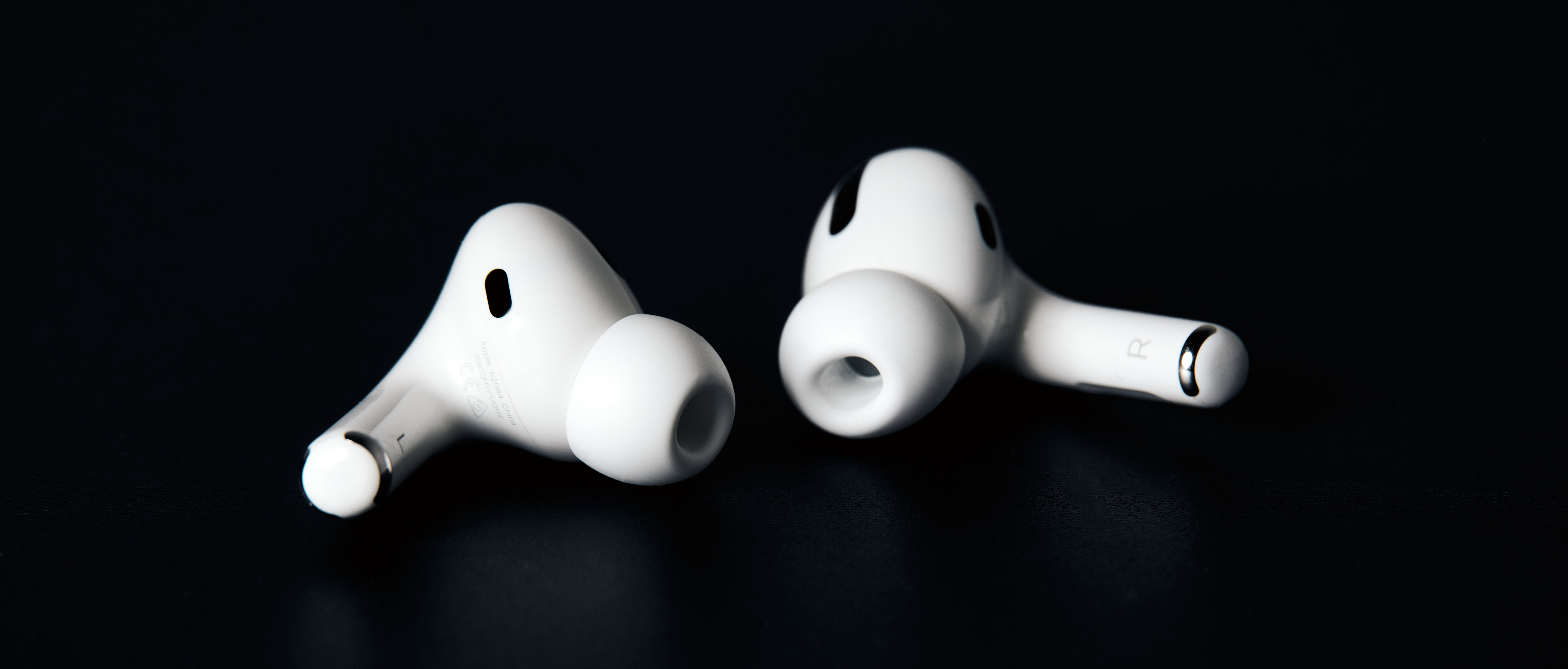 A closeup photograph of a pair of Airpods Pro against a black background.