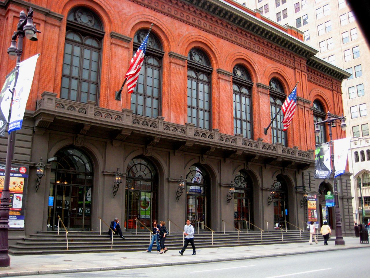 A photograph of the front facade of the Philadelphia Academy of Music, a brick and concrete building with two rows of large arched windows.