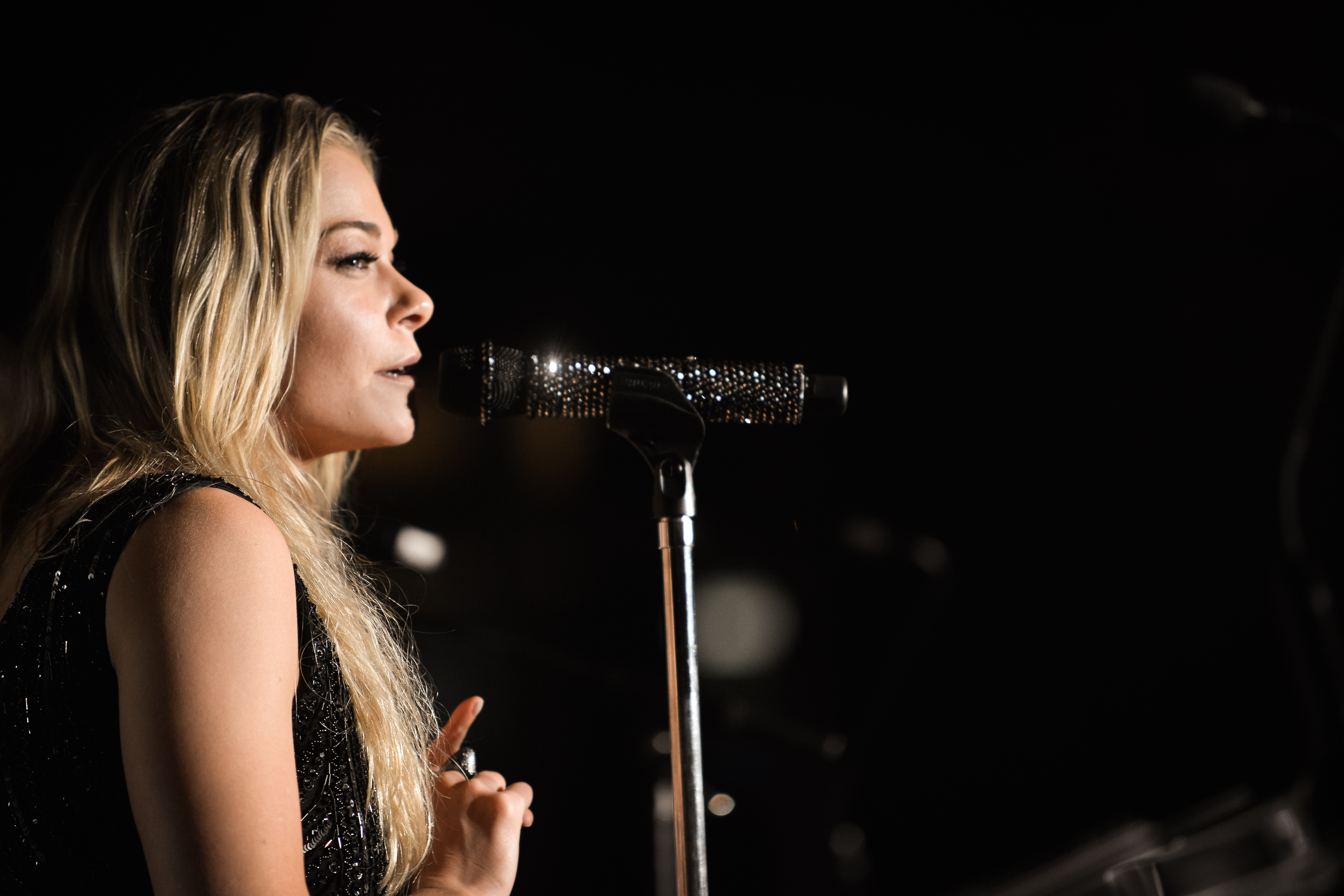 A photograph of Shea Diamond singing on an outdoor stage.