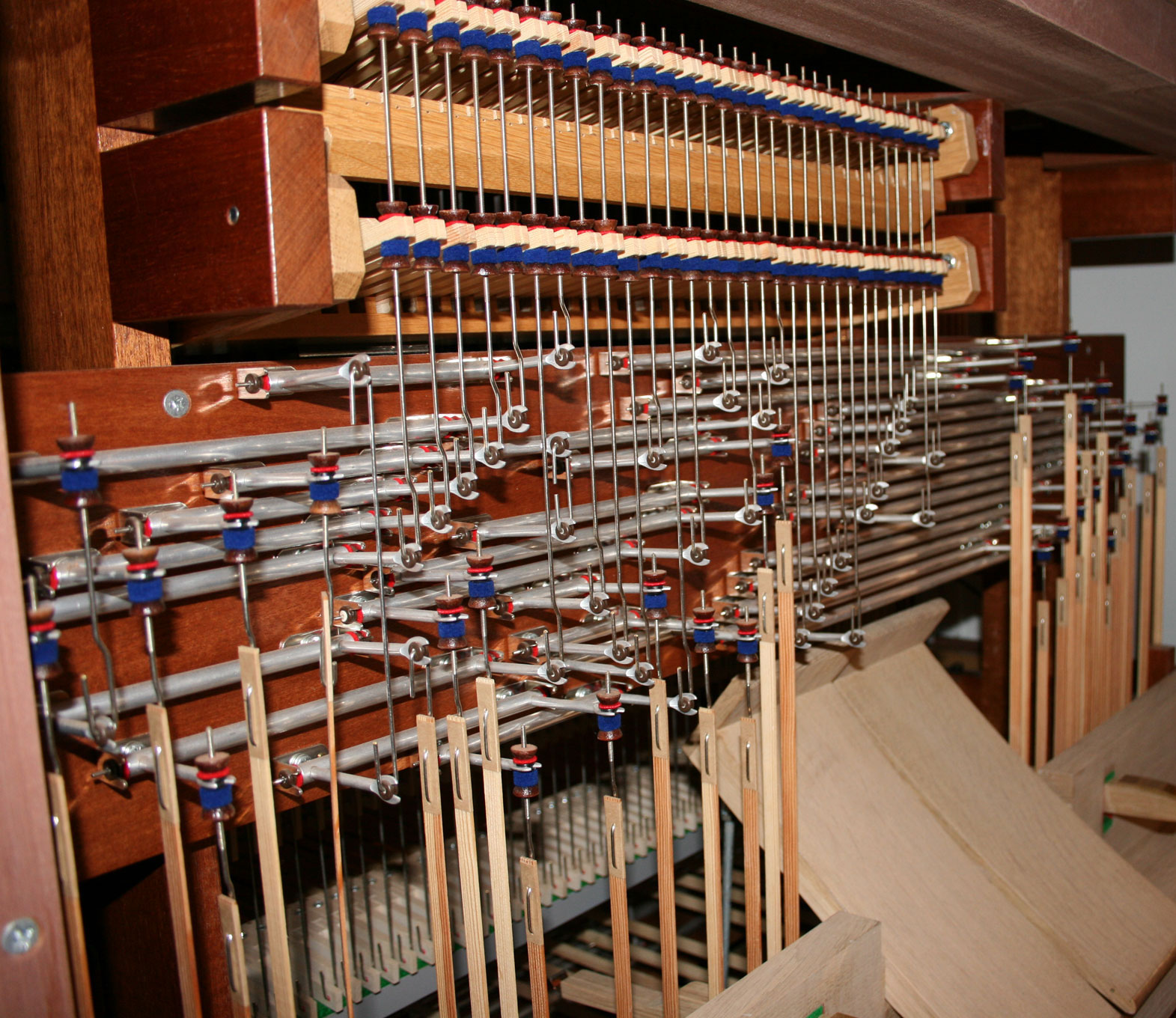A photograph of the inside of an organ console, showing a densely complex system of rods, arms, joints and levers controlled by the stops and manuals.
