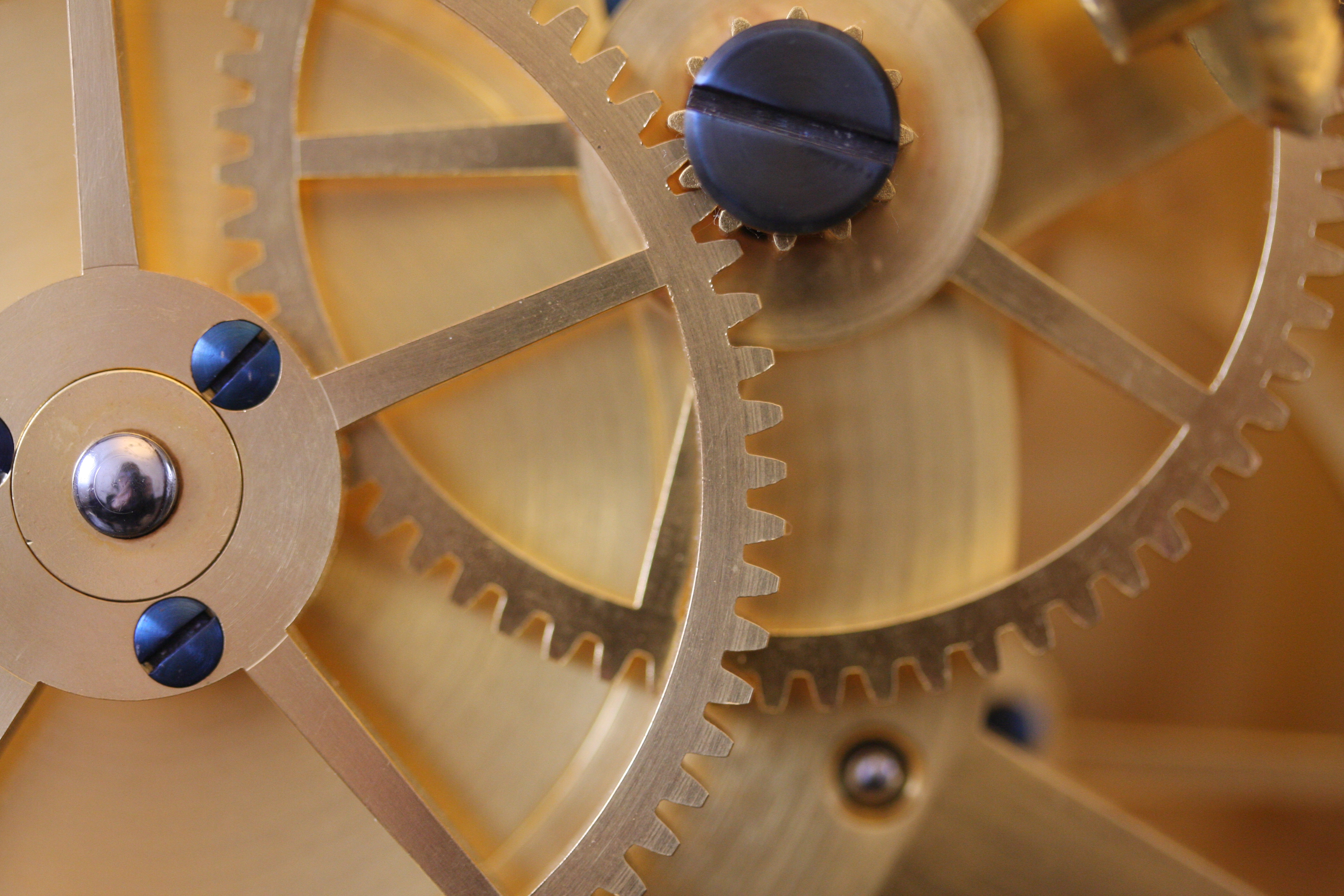A closeup of two wooden gears interlocked with one another. The light wood gears are held in place with black screws.